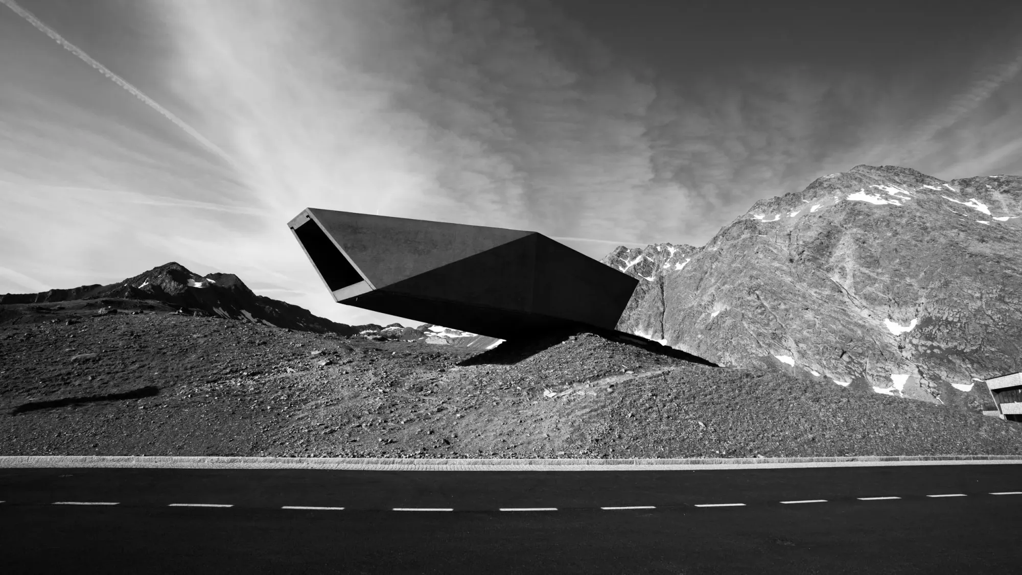 Skulptur an einer alpinen Passstraße vor Bergkulisse