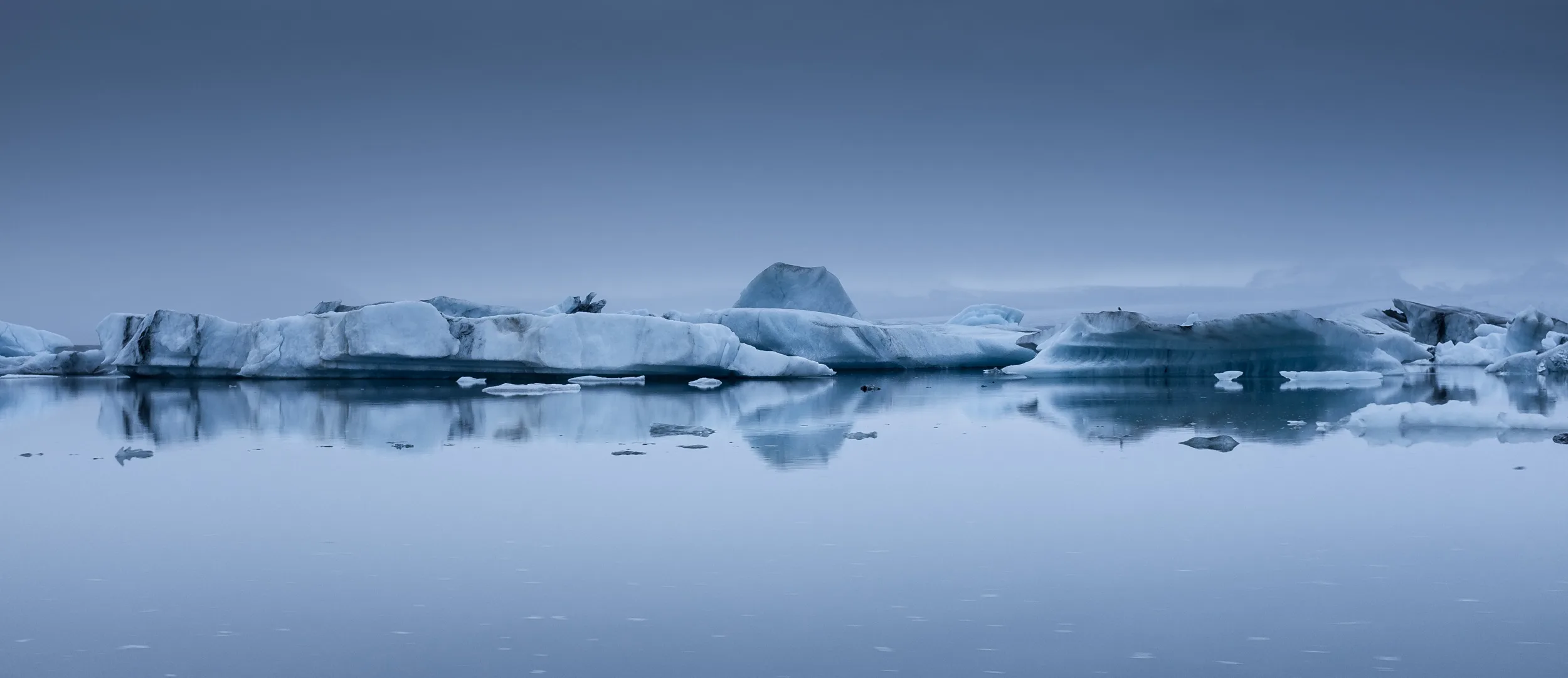 Spiegelung der Eisberge in der ruhigen Gletscherlagune auf Island