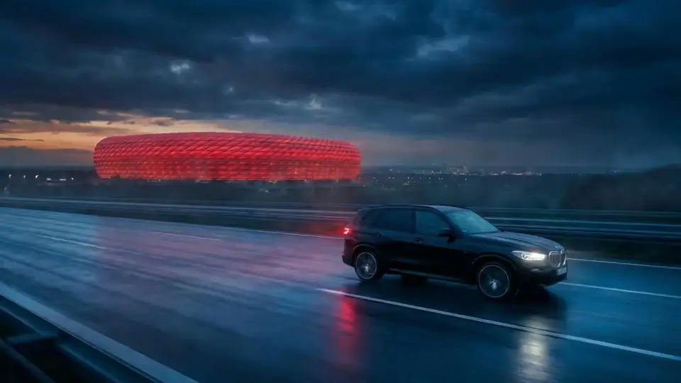 BMW X5 auf nasser Autobahn vor der rot beleuchteten Arena in München – Vorschau auf den Scroll-Storytelling-Showcase Matchday